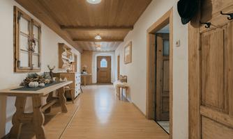 An inviting hallway with wooden floors and a warm atmosphere. Decorative elements hang on the wall and there is a table with autumn decor.