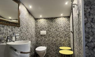 A modern bathroom with a stylish wall design and an elegant sink. There is a toilet and two yellow tables for added comfort.