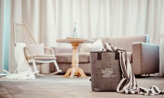 A stylish room with a cozy armchair and a side table. A bag is in the foreground, decorated with a towel.