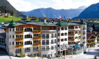 A modern hotel building with a magnificent mountain view. It has several balconies and an inviting entrance hall.
