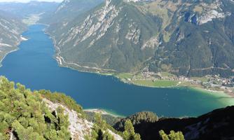 An impressive mountain landscape with a clear blue lake and green meadows. The surrounding mountains give the scene a majestic atmosphere.
