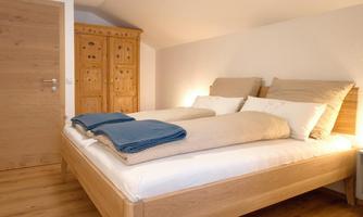 A cozy bedroom with a double bed and wooden floor. The soft lighting creates a relaxed atmosphere.