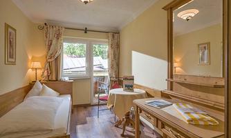 A cozy room with a single bed and a small table.  
Large windows provide plenty of daylight and a view outside.