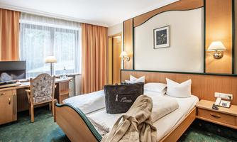 A cozy hotel room with a double bed and comfortable pillows. The room is bright and friendly, equipped with a desk and a television.