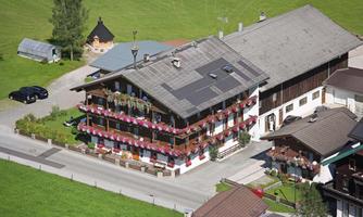 A charming building with balconies adorned with flowers. It is located in a green landscape, surrounded by other buildings and vehicles.