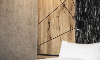 A modern bedroom with an elegant bed and stylish pendant lights. The walls are designed with wood and concrete, creating a cozy atmosphere.