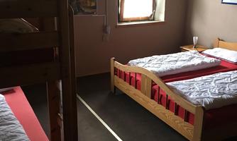 A cozy bedroom with two single beds and a bunk bed. There are windows that provide a lot of daylight.