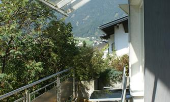 A small balcony with a view of the mountains. There is a chair and plenty of daylight through the glass roof.