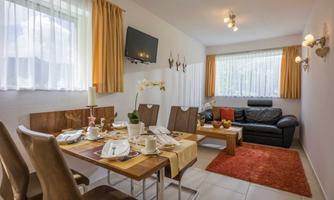 An inviting living room with a dining table and comfortable seating. Bright curtains and a cozy atmosphere create a pleasant environment.