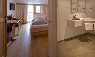 A cozy room with a double bed and natural light. A modern bathroom with elegant fixtures can also be seen.