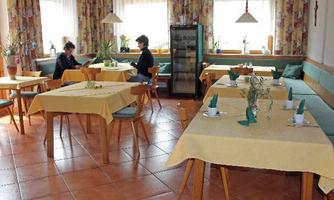 A cozy restaurant with tables covered in yellow tablecloths. Two individuals are sitting at separate tables enjoying their meal.