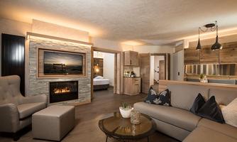 A modern living room with a cozy sofa and a coffee table. The fireplace creates a warm atmosphere, and the wood details create an inviting ambiance.