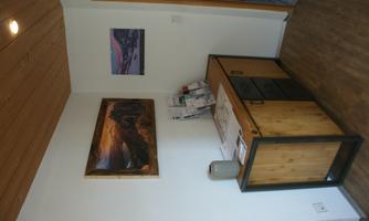 A friendly entrance area with a wooden table and decorative pictures on the wall. On the table are some brochures and a vase.