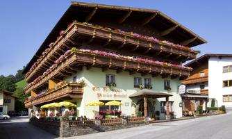A traditional building in alpine style with balconies adorned with flowers. The outdoor area with umbrellas invites you to linger.