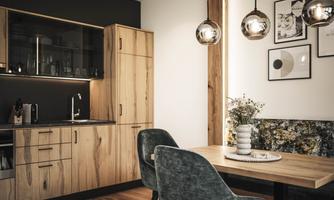 A modern kitchen with wooden cabinets and elegant, round lamps. The dining table is simply set and offers space for cozy meals.