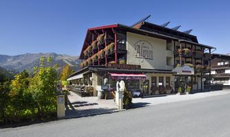 An inviting hotel with a traditional Alpine style. Surrounded by mountains and colorful flowers.