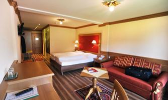 A cozy hotel room with a double bed and a seating area. The room has warm lighting and an inviting atmosphere.