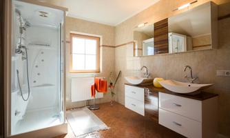 A modern bathroom with a shower and two sinks. The warm colors and natural light create an inviting atmosphere.