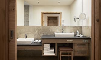 A modern bathroom with wooden accents and a stylish sink. Clean towels are neatly stacked, and the room has an inviting feel.