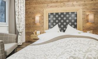 A cozy bedroom with wood paneling and a large bed. The room is friendly and modernly furnished.