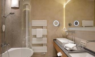 A modern bathroom with a bathtub and a shower. The walls are in warm tones and there is plenty of light.