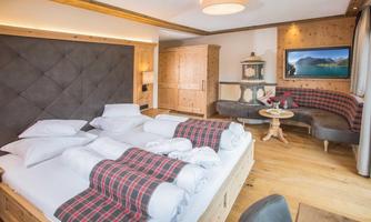 A modern bedroom with a large bed and wooden paneling. The decor is cozy and inviting, with a seating area and a television.