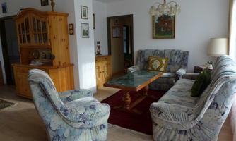 A cozy living room with blue and gray sofas. A wooden table and a display cabinet complement the decor.