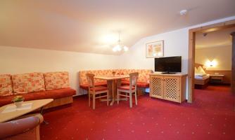 A cozy living area with a sitting area and a table. The room has a warm, inviting carpet and is brightly lit.