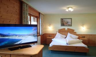 A cozy hotel room with a large bed and a television. The walls are painted in warm colors, and there is a beautiful picture on the wall.