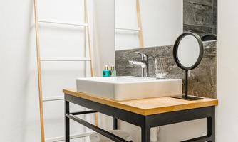 A modern bathroom with a sink on a wooden shelf. Towels are neatly stacked and a mirror complements the decor.