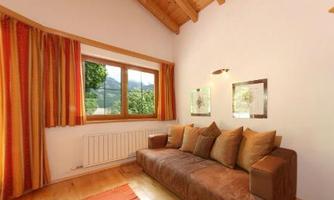 A cozy living space with a brown couch and colorful curtains. Through the window, you can see the green landscape outside.
