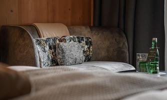 A modern room with a comfortable sofa and light wooden walls. Next to the sofa, water bottles and glasses are ready.
