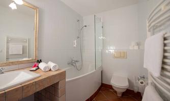 A modern bathroom with a bathtub and a shower. The walls are brightly tiled, and a sink with an elegant mirror completes the space.