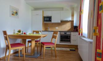 A modern kitchen with a dining area. The table is set with dishes and the furniture is made of light wood.