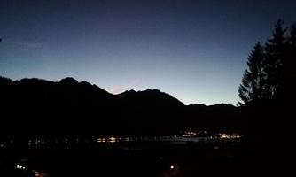 A peaceful mountain landscape at twilight. In the background, silhouettes of mountains and a gentle glow on the horizon can be seen.
