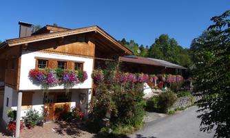 A charming house in alpine style with blooming balconies. The surroundings are green and sunny, ideal for a peaceful getaway.