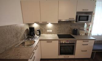 A modern kitchen with bright cabinets and a stone countertop. It is equipped with appliances such as a stove, an oven, and a microwave.