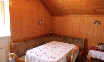 A cozy dining area with wooden walls and a decorated table. The bench invites you to linger.