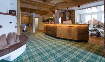 An elegant reception desk made of wood in a modern space. The floor is covered with a checkered rug in shades of green.