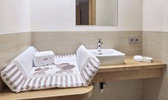 A modern bathroom with a changing table and a sink. The walls are light and simply designed.