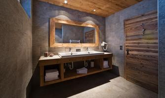 A modern bathroom with wooden details and a large mirror. The soft color tones and elegant design create an inviting atmosphere.