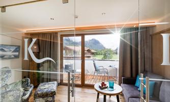 A modern apartment with large windows and a view of the mountains. Cozy furniture and a bright room create an inviting atmosphere.