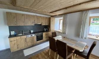A modern kitchen with wooden shelves and a dining area. Bright colors create an inviting atmosphere.