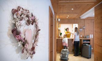 An inviting reception area with a decorative crown of dried flowers. In the background, people are at the reception and chatting.