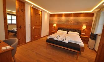 A cozy bedroom with a double bed and warm wooden decor. Soft lighting and a relaxing atmosphere create an inviting ambiance.