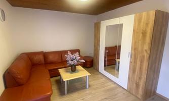 A cozy living room with a red leather couch and a coffee table. A white cabinet with a mirror stands against the wall.