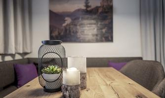 A stylish table with a modern lamp and decorative candles. In the background, a picture of a landscape hangs.
