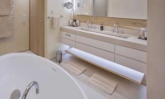 A modern bathroom with a freestanding bathtub and a double sink. The walls are light and the decor appears elegant and minimalist.