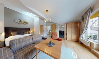 A modern room with a cozy sofa, a table, and a large window. The decor is stylish and inviting.