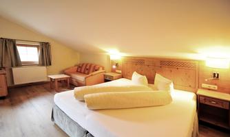 A cozy bedroom with a large double bed and two pillows. The walls are bright and the atmosphere feels inviting and friendly.
